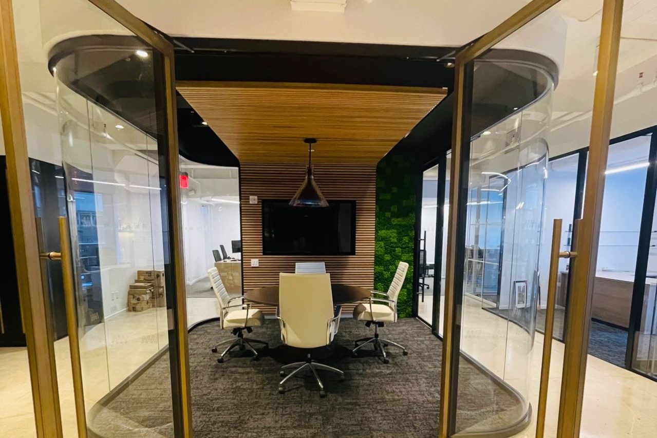 Fishbowl meeting room with curved glass and bi-parting doors in MetroWall's showroom.