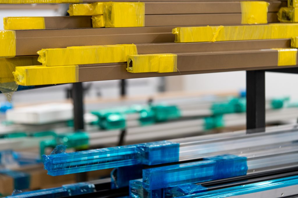 Loose aluminum extrusions wrapped with cellophane in manufacturing facility.