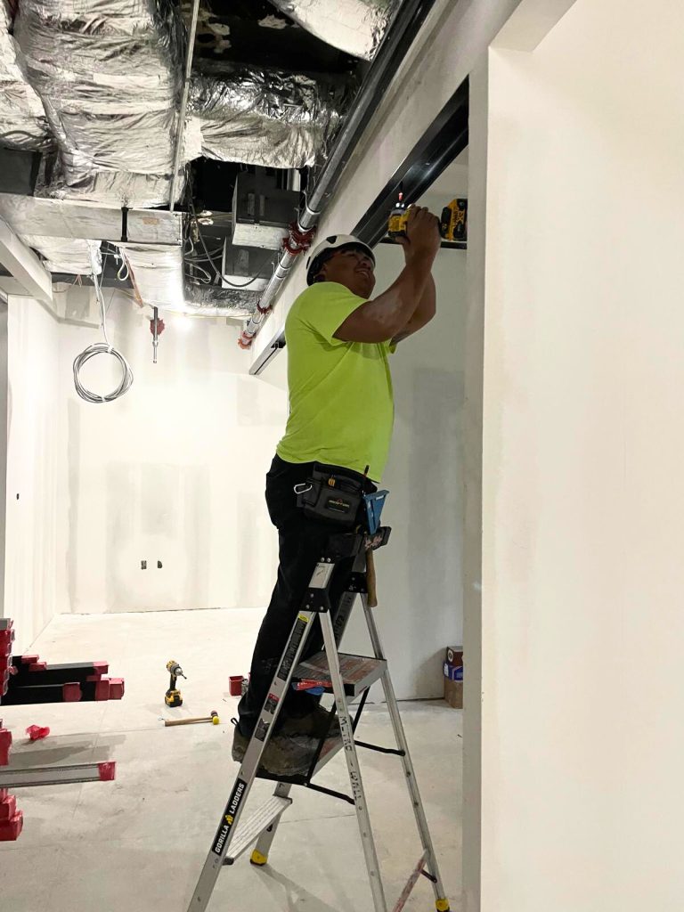MetroWall installer screwing trim into drywall.